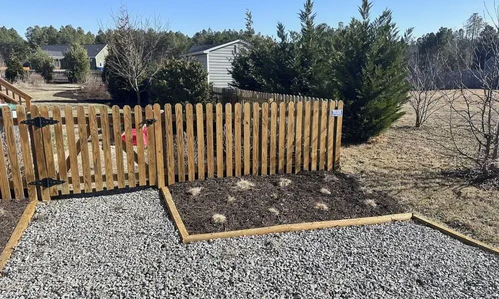 A small section within a lawn area with a wooden boundary wall is dug out for mulch installation