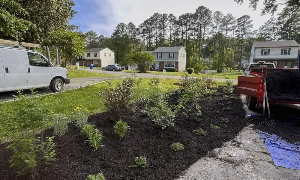 Mulch installation with some plants added on a slope within a section of a big lawn