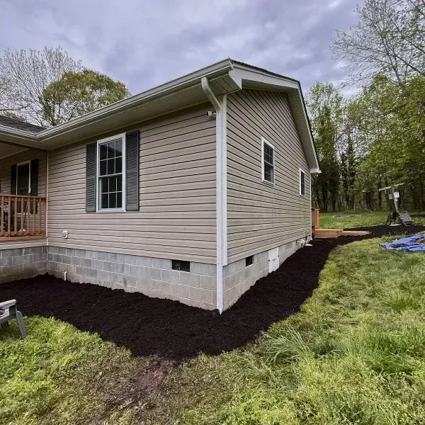 Wide Angle Shot Of A Small Corner House With Its Foundation Dug For Mulch Spreading For Seeding And A Big Lawn Area Around