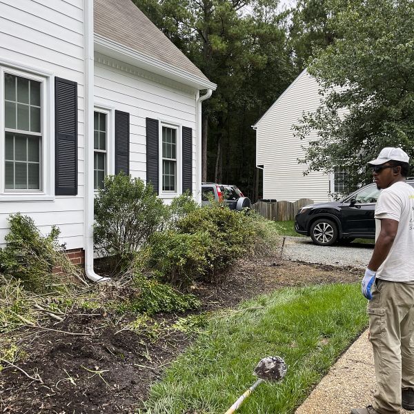A Professional Standing In Front Of A House With A Lawn, Inspecting The Area Before Brush Removal Or Brush Cutting